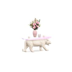 a white cat figurine sitting next to a vase with pink flowers on it