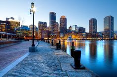 the city skyline is lit up at night, and it's reflecting in the water