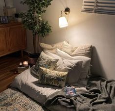 a bed with pillows, blankets and a lamp on top of it in a bedroom