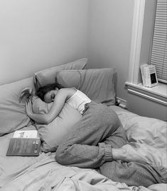 a woman laying in bed with her head on the pillow, reading a book and sleeping