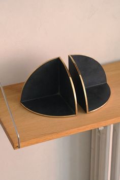 two black and gold plates sitting on top of a wooden shelf