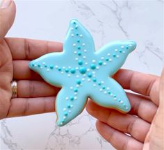 a hand holding a blue starfish shaped cookie