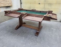 a table made out of wood sitting on top of a cement floor next to a building