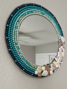 a mirror with beads and seashells hanging on the wall