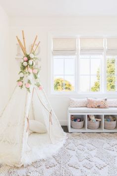 a teepee is in the corner of a room with white walls and flooring