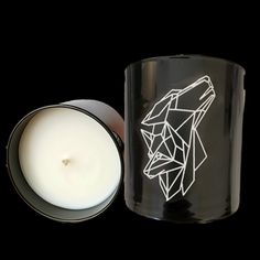 a black candle holder with a white wolf design on it and a lit candle next to it