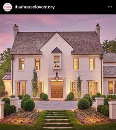 a white house with lots of windows and steps leading up to the front door at dusk