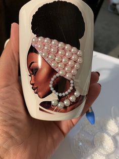 a hand holding up a cup with an image of a woman wearing pearls on it