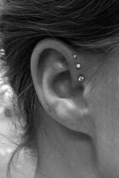 a woman's ear with three piercings on it