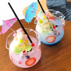 two glasses filled with ice cream and strawberries on top of a wooden table next to each other