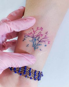 a woman's arm with a tattoo on it that has blue and pink flowers