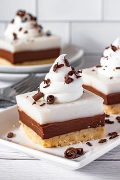 two pieces of chocolate haupia bars on a white plate with whipped cream and chocolate shavings