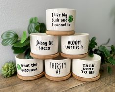 five ceramic bowls with words on them sitting on a wooden table next to some plants