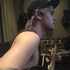 a young man is playing the guitar in his living room