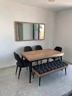 a dining room table with black chairs and a bench in front of the mirror on the wall