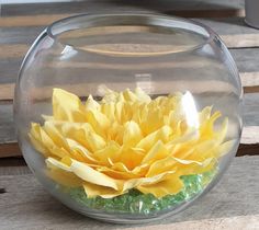 a glass bowl filled with yellow flowers on top of a wooden table