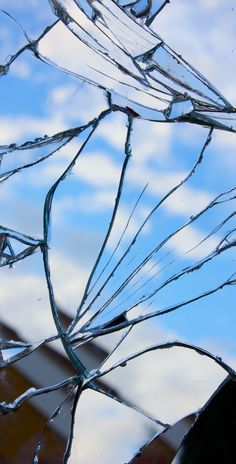 a broken glass window with the sky in the background