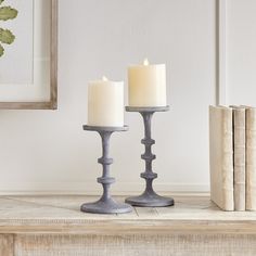 two candles sitting on top of a table next to an old book and some books