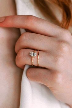 a woman's hand wearing a gold ring with an oval shaped diamond on it