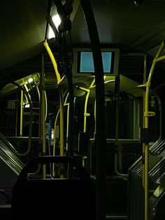 the interior of a public transit bus with yellow handrails and seats at night