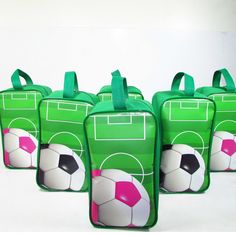 four green bags with soccer balls painted on the front and back, all lined up together