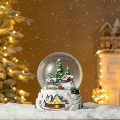 a snow globe sitting on top of a table next to a christmas tree with lights