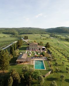 an aerial view of a large house in the middle of a field with a swimming pool