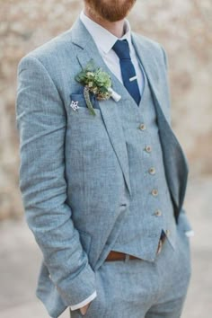 a man with a beard wearing a blue suit and flower boutonniere on his lapel