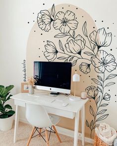 a white desk with a computer on it in front of a flowered wall mural