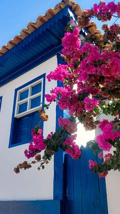 a blue and white house with pink flowers on the outside