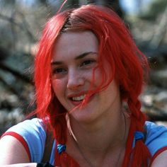 a woman with red hair is smiling at the camera