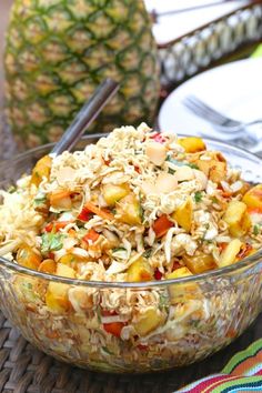 a bowl filled with rice and vegetables on top of a table next to two pineapples