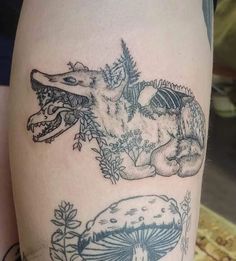 an image of a tattoo on the leg of a woman's leg with two dinosaurs and mushrooms