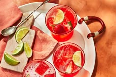 three glasses of watermelon lemonade on a plate with limes and spoons