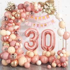 a pink and white balloon arch with the number 30 surrounded by balloons in front of it