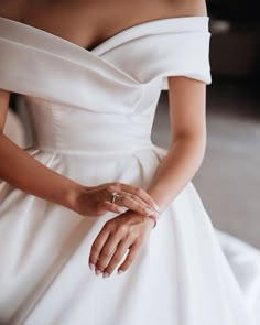 a woman in a white dress is holding her hands on her waist and wearing an engagement ring