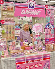 a woman standing in front of a booth at a toy store with lots of items on display