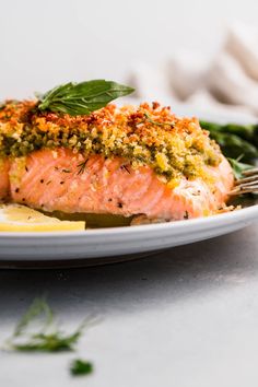 a white plate topped with salmon covered in seasoning and garnished with herbs