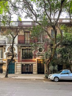 a blue car parked in front of a tall building with balconies on the windows