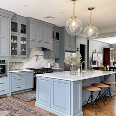 a large kitchen with blue cabinets and white counter tops, an island in the middle is surrounded by stools