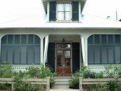 a house with green shutters on the front door and steps leading up to it