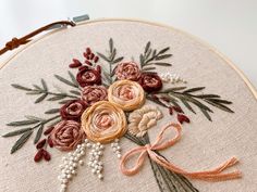 a close up of a embroidery on a hoop with flowers and leaves in the center