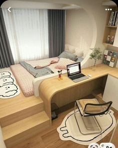 a laptop computer sitting on top of a wooden desk in front of a bed with hello kitty pillows