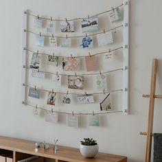 a wooden table topped with a white vase filled with flowers and pictures hanging from clothes pins