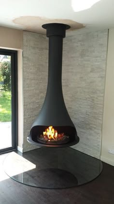 a fire place in the middle of a room with a glass table and door leading outside