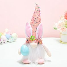 a pink and white stuffed animal with some balloons in it's mouth on a table