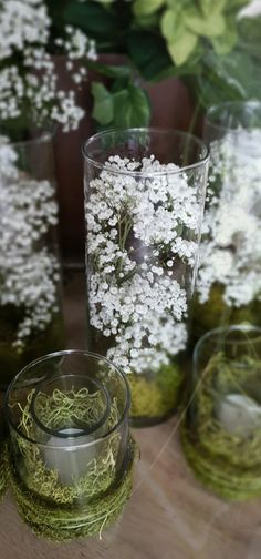 three glass vases filled with white flowers on top of a table