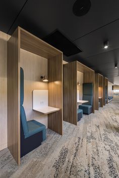 an empty office with blue chairs and wooden partitions on the wall to divide it from the rest of the room