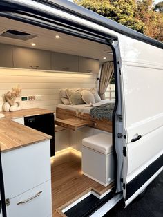 the interior of a camper van that is white and has wood flooring on it