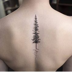 a woman's back with a pine tree tattoo on her left side ribcage